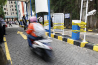 Pengendara motor melintasi barrier gate yang sudah di segel.
